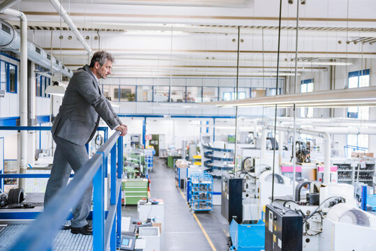 Thoughtful businessman leaning on railing at factory