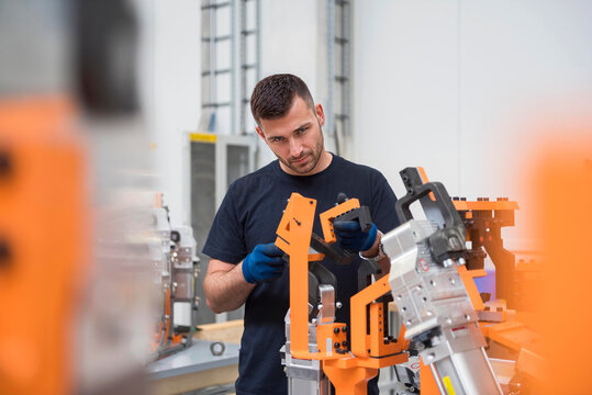 Engineer examining and repairing robotics in factory