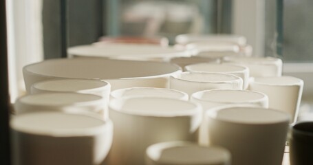 Row of Freshly Molded Ceramic Pots Drying in Sunlit Workshop