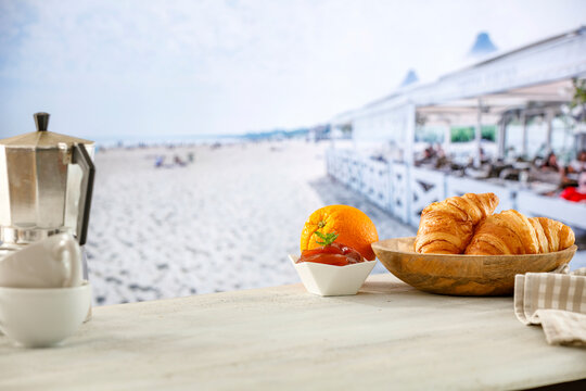 Summer continental breakfast on a beach. Croissants, jam and fruit on a wooden table. Summer table background for montage product display. Copy space for food and drink and products.