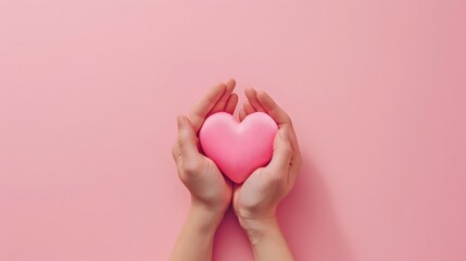 Fototapeta premium A pair of hands holding pink heart on pastel background, top view with copy space concept