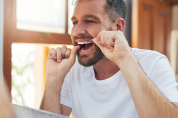 Man, teeth and flossing with morning routine in home for grooming, oral care and hygiene for wellness. Male person, reflection and mouth for dental health, fresh breath and bathroom with confidence