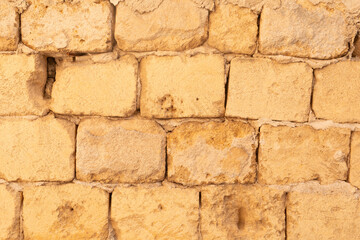 A wall of weathered yellow stones