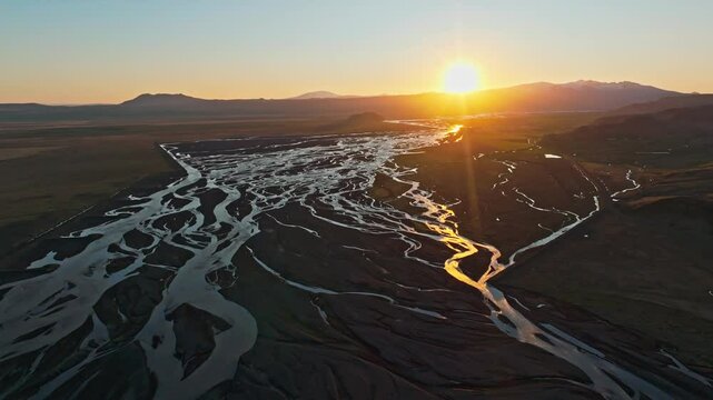 View from above, stunning landscape at sunset with a patterns created in the volcanic sands of Iceland as glaciers melt the water flows as rivers out to sea. 
