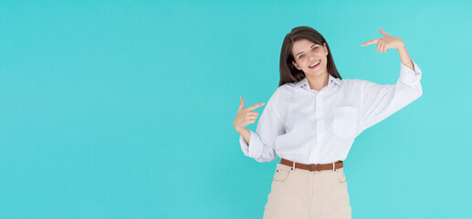 Young woman standing over blue background looking confident with smile on face, pointing oneself...