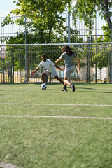 Obraz premium Two young adult soccer players are having fun playing soccer on a field on a sunny day