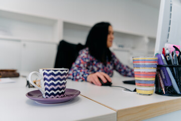 Businesswoman Working on Computer with Coffee Mug in Foreground