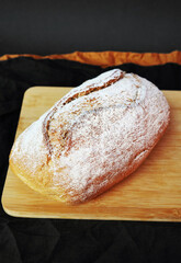 Homemade grain bread on a wooden board next to a knife on a linen napkin
