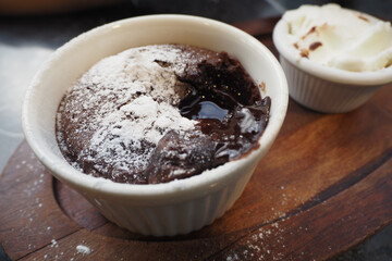 Delicious Chocolate Lava Cake with Powdered Sugar and Whipped Cream on Wooden Plate