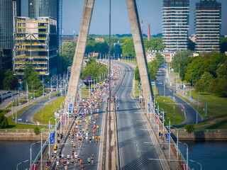 Aerial shot of marathon participants running across a distinctive bridge with two large pillars in...