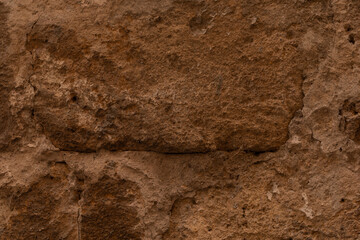 A weathered stone wall with cracks and uneven texture