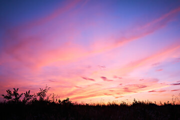 Dusk, sunset sky clouds in the evening with colorful orange, yellow, pink and red sunlight and dramatic storm clouds in the twilight sky, landscape horizon, nature, summer background.