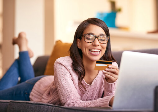 Debit card, laptop and woman relax in home with happiness for paying bills with debt free lifestyle. Smile, computer and female person with internet banking app to apply for mortgage in apartment.
