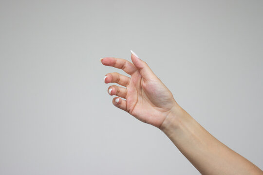 A woman's hand is open and holding something like a bottle. Gesture isolated on gray background. The girl gives some object. Product presentation concept or mockup with copy space. Advertising