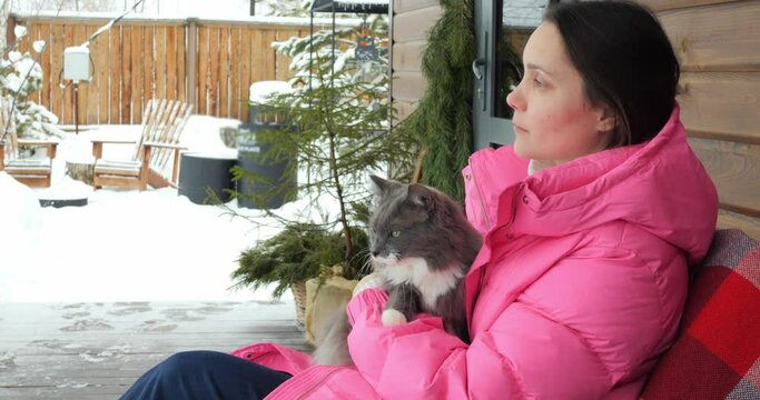 Animal behaviorist cradling cat on snowy porch. Calm cat enjoys winter scene, zookeepers gentle touch. Cat with zookeeper, snowy serenity cat experience. Peaceful and affectionate winter moment.