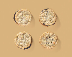 Four chocolate chip cookies arranged in a neat pattern on a brown background. The close-up view highlights their crunchy texture and chocolate-filled centers, making them look delicious and inviting. 