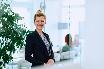 Portrait of a Blonde Businesswoman in a Modern Office with Her Workspace and Colleagues in the...