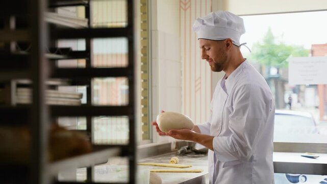 Pastry master making and kneading dough for bread or croissants to sell in his shop