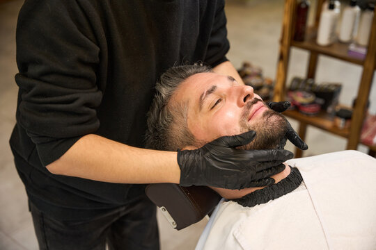 Barber applying the beard balm to style and maintain flyaways