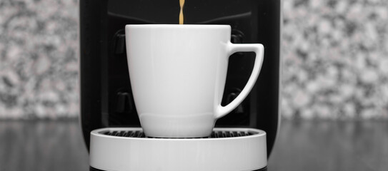 Kawa z ekspresu ciśnieniowego nalewana do filiżanki z bliska, izolowany pojedynczy kubek © Paweł Kacperek