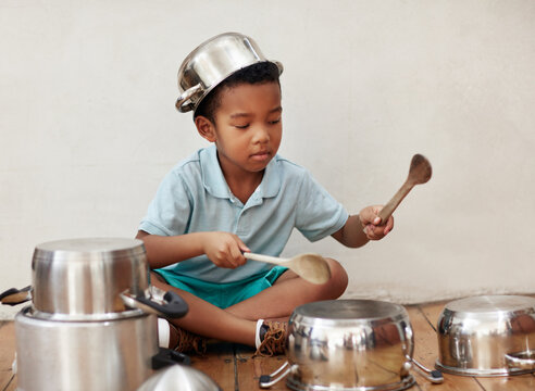 House, kid and noise of pots for drum, rhythm and coordination for motor skills with metal beat. Creativity, boy musician and talent with sound, imagination and fantasy for childhood on floor in home
