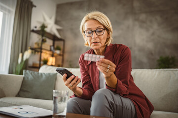 Mature woman hold the medicine and read instructions on mobile phone