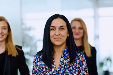 Confident businesswomen stride through the office hallway, deep in discussion.