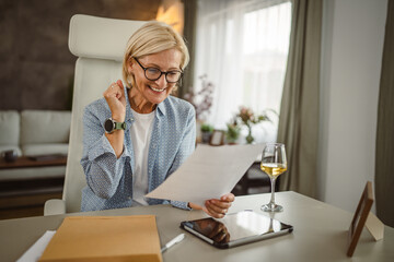 Mature woman work from home read letter post envelope with good news