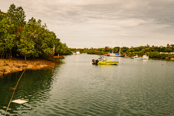 Naklejka premium Silhouette of boats against palm trees at Sunset in Mtwapa Creek, Mtwapa Town in Kenya