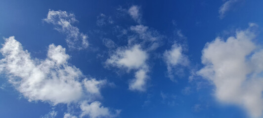 White clouds are moving slowly in the blue sky on a sunny day