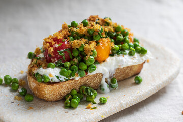 Burrata cheese with grilled green peas, pickled tomatoes and breadcrumbs on toast