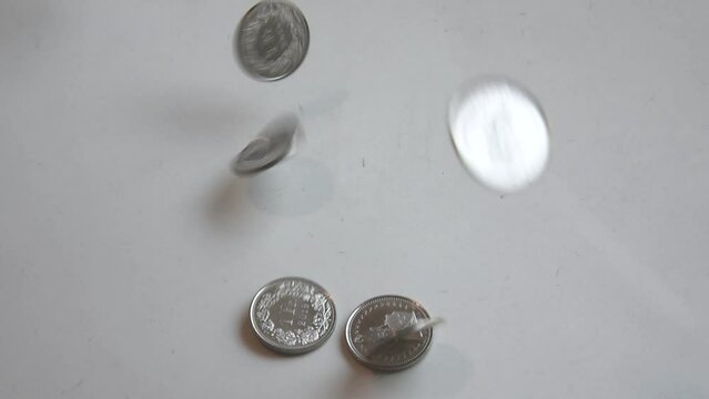 new coins falling on a white surface