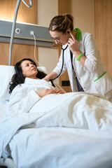 Obraz premium Doctor listening to woman with stethoscope