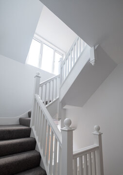 Renovated, white painted, wooden staircase with simple vertical slats, in an Edwardian house, north west London UK.