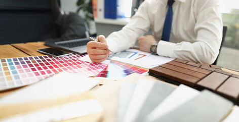 Close-up of interior designer man work on new project, palette on workplace. Selection of material colour from samples. Architect, creativity, art concept