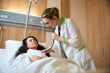 Young doctor listening to woman with stethoscope