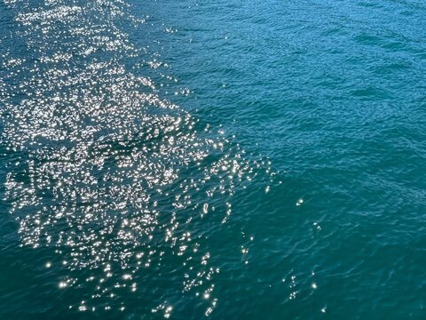 Blue sea water with sun glare on rippled surface 