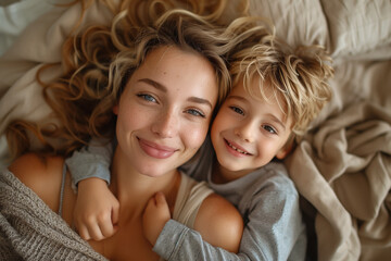 Top view of a happy mother and son laying on bed, hugging each other laughing together. love. Soft...