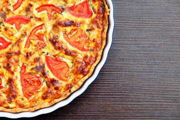 Delicious homemade quiche with fresh tomato slices and melted cheese, baked to perfection in a ceramic dish. A perfect savory pie for breakfast, brunch, or dinner.
