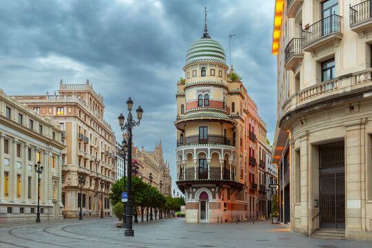 Fototapeta Old houses on Constitution Avenue in the light of lanterns at dawn, Seville, Andalusia, Spain