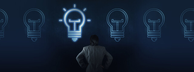 Businessman contemplating glowing lightbulb ideas,One lightbulb glows brightly, symbolizing a...