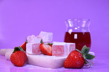 Turkish delight with fresh strawberries and fruit tea in a glass glass