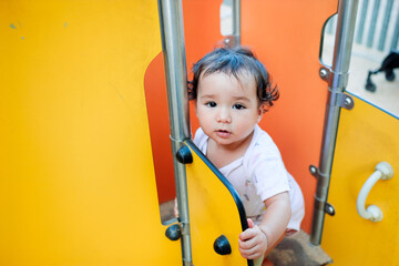 close up of baby girl playing in a children's playground, 2 years old girl in the children park, portrait looking in camera