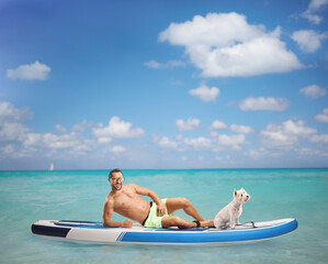 Young man laying on a SUP with a dog