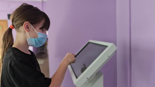 Young girl uses touch screen kiosk in public place