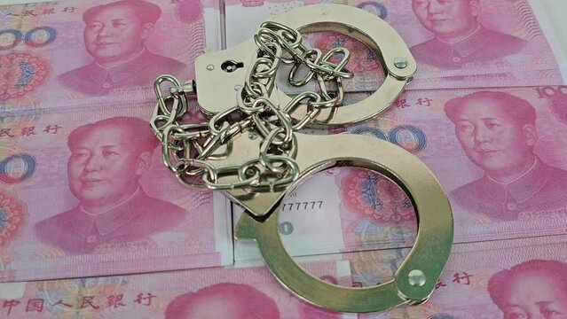 Handcuffs Resting on Chinese Yuan Banknotes