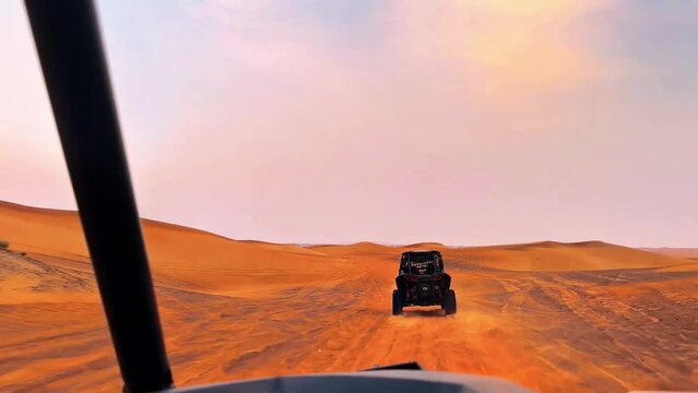 Silhouette dune buggy explores the abandoned terrain of the sweltering desert during a sunset sandstorm. High quality 4k footage