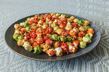 A rainbow of sweet popcorn in a plate on a tablecloth