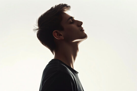 Silhouette of handsome man in black t-shirt on white background, isolated portrait of young guy with short hair and sidecut looking up, profile view, isolated


