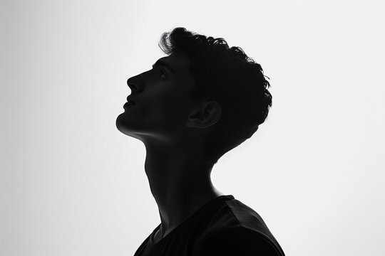 Silhouette of handsome man in black t-shirt on white background, isolated portrait of young guy with short hair and sidecut looking up, profile view, isolated


